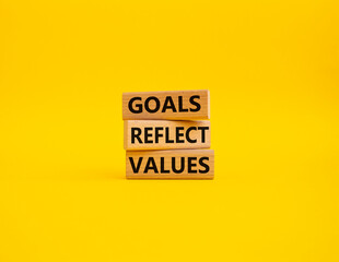 Goals reflect values symbol. Concept words Goals reflect values on wooden blocks. Beautiful yellow background. Business and Goals reflect values concept. Copy space