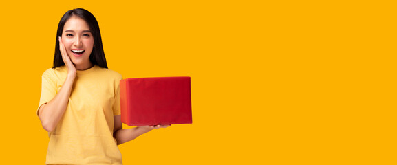 Surprised young asian woman holding red gift box Look at camera with excited face Standing over...