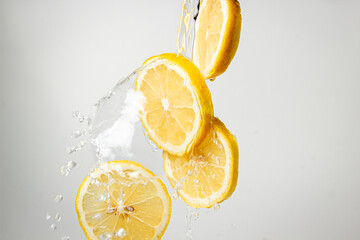 Obraz na płótnie Canvas Water pours on lemon slices on a white background. Lemon freshness.