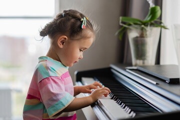 Fototapeta na wymiar Side view of cute asian girl playing piano at home