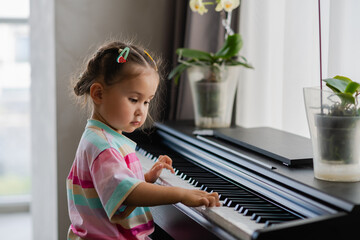 Cute little girl playing piano at a music school.