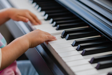 Fototapeta na wymiar Hands of little girl playing piano, selective focus