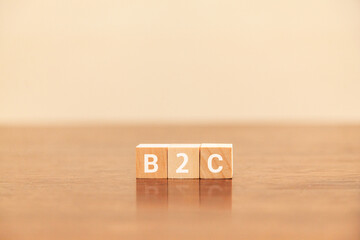 B2C。企業と一般消費者の取引。Business to Business。木製のブロックに描かれているB2Cの文字。木製のテーブルの背景。