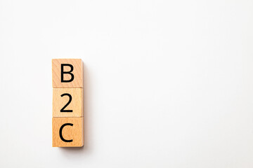 B2C。企業と一般消費者の取引。Business to Customer。木製のブロックに描かれているB2Cの文字。木製のテーブルの背景。