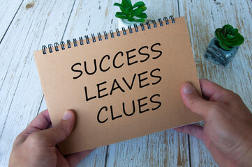 Success leaves clues text written on brown notepad. Motivational concept.