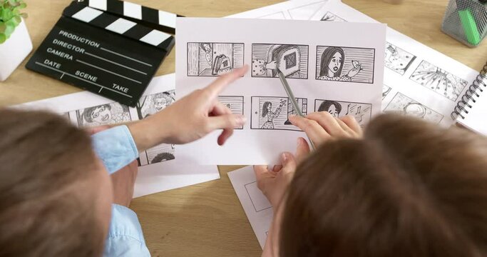The director and cameraman examine the frames of the storyboard on paper. Drawn characters for the film. Storytelling concept.