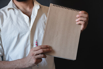 man in a white shirt holding brown notebook