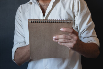 man in a white shirt holding brown notebook