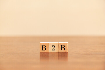 企業間取引。B2B。Business to Business。木製のブロックに描かれているB2Bの文字。木製のテーブルの背景。