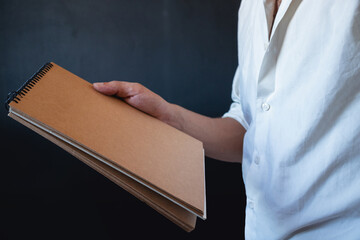 man in a white shirt holding brown notebook
