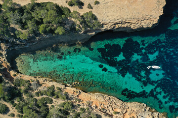 Fototapeta premium Aerial drone top down photo of boat anchored in exotic island covered with pine trees
