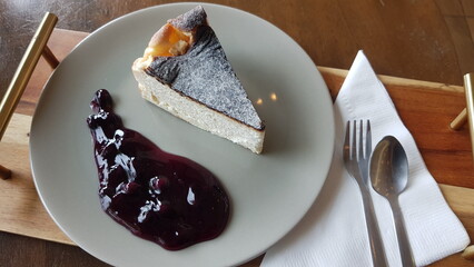 Cheesecake and blueberry jam on a white plate.