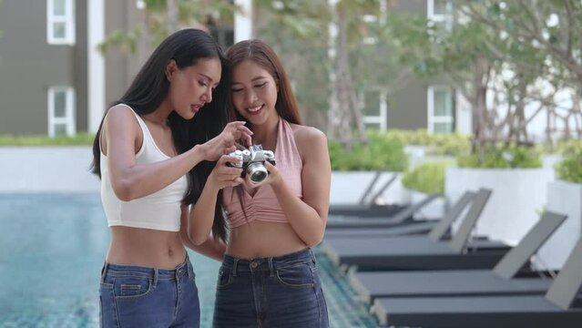 Beautiful Asian girls traveling together and taking pictures at the hotel pool, Summer travel, Good day.