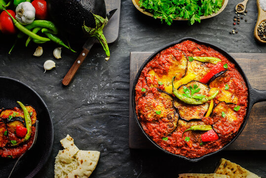 Arabic cuisine; Egyptian traditional food Moussaka. It contains fried eggplant(aubergine),colored bell peppers,chill peppers and garlic tomato sauce.Served with pita bread. Top view with close-up.