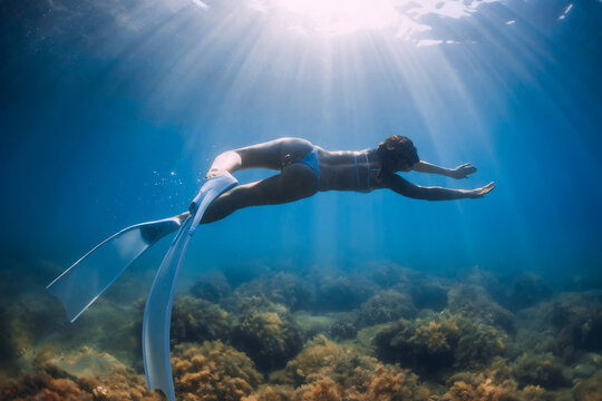 Woman freediver glides with fins. Freediving and beautiful sunlight in ocean