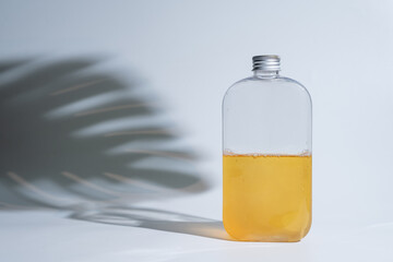 drink in a glass bottle on white background with hard or Harsh shadows and sunlight of leaves tree branch falling on wall. modern and minimal product design. cold refreshment beverage.