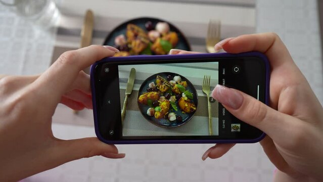 Girl take pictures of grilled peach salad with mozzarella, using smartphone. Female hands take photos of food by modern smartphone. Close up, 4K