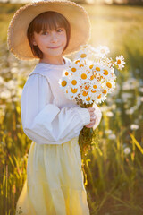 süßes kleines Mädchen mit einem Strauß Gänseblümchen auf einer sonnigen Blumenwiese