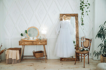 Wedding dress on a large mirror next to the table in a bright interior
