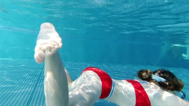 Slow motion of little girl practice swim and dive underwater in swimming pool at summer vacation