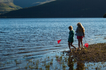 Fototapeta na wymiar Children having fun playing on Loch Lomond Beech 