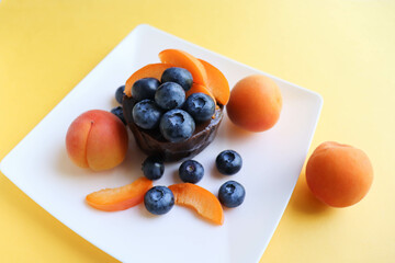 summer desserts. chocolate dessert with blueberries apricots on a white plate