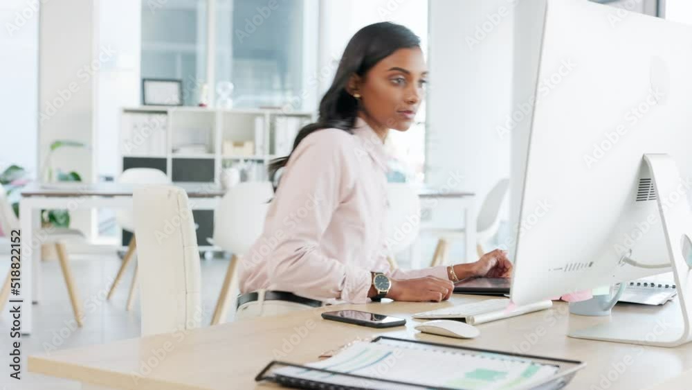 Aufkleber Female secretary browsing online and typing an email on a desktop computer in an office alone. One serious Indian assistant using a digital tablet and working on a plan or marketing strategy