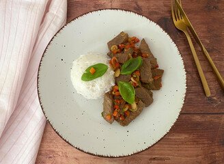 Stir fry, marinated, fried strips of beef with chili pepper, basil and spring onions, served with rice.