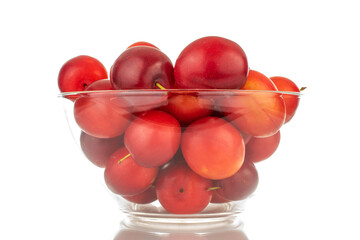 Several ripe juicy cherry plums in a glass dish, close-up, isolated on a white background.