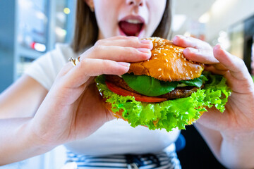Vegetarian hamburger healthy vegan burger. Cute cheerful girl eating veggie sandwich with salad, avocado, vegetable. Vegan burger healthy diet food.
