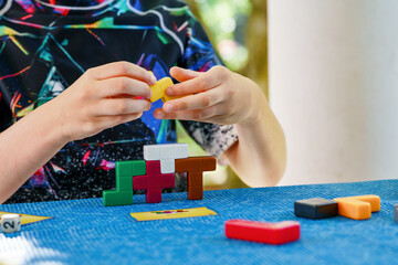 School boy playing board game with colorful bricks. Happy child build tower of wooden blocks, developing fine motor skills, home joint games. Leisure activities for children at home.