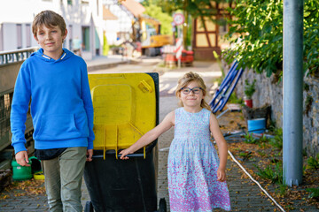 Little preschool girl with glasses and school kid boy taking garbage can. children learning waste...