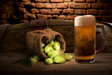 Beer. Still life with Vintage beer barrel and glass light beer. Fresh amber beer concept. Green hop...