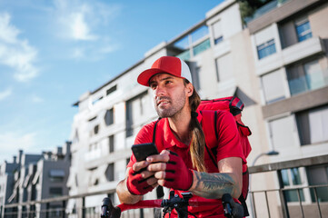 Man who works delivering food by courier at home consulting the smart phone.