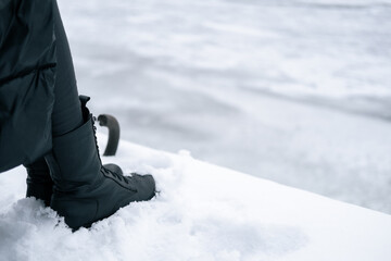 Fototapeta na wymiar Black women's high boots in the snow.