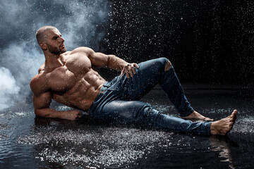 Muscular man under the rain in studio. Sexy male in water drops, abs