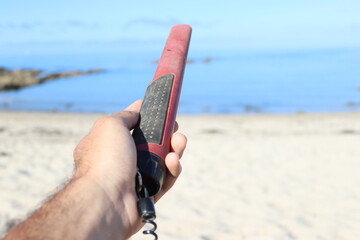 pinpointer in a hand at the beach on the sand