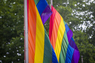 Close Up rainbow gay pride flag outside on a street. Symbol of the Lesbian Bisexual Transgender LGBT community waving in wind against cloudy sky. Social movement for freedom and equliaty. Copy Space