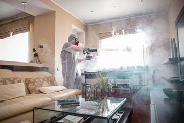 disinfection of the room against viruses. Man in quarantine clothes disinfecting room