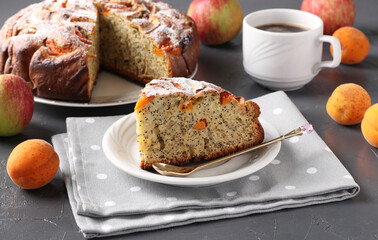 Homemade apricots pie with poppy seeds and apples, with cup of coffee on gray background