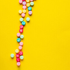 Some plastic beads with letters on yellow background