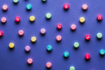 Bright multicolored alphabet background. Multicolored bead letters on blue background. Flat Lay.