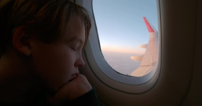 Tired boy looking out airplane window
