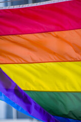 Close Up rainbow gay pride flag outside on a street. Symbol of the Lesbian Bisexual Transgender LGBT community waving in wind against cloudy sky. Social movement for freedom and equliaty. Copy Space