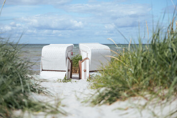 Romantic sea scene at white beach with wicker beach chair at summer sunny day - obrazy, fototapety, plakaty