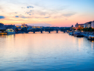 Obraz premium Prague, Czech Republic - June 2022: View with the Charles Bridge main touristic attraction at sunset. Medieval stone arch bridge over Vltava river in Prague