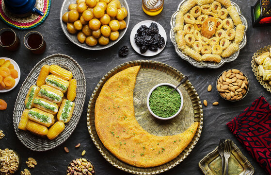 Arabic Cuisine: Middle Eastern desserts. Delicious collection of Ramadan traditional desserts. Served with tasty nuts, dried fruits, honey syrup and oriental tea. Top view with close up.