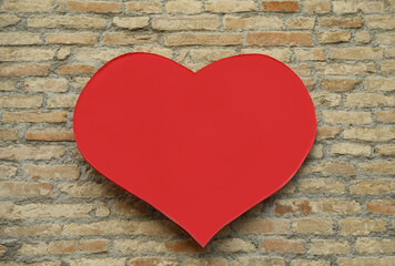 Empty heart shaped sign on brick wall. Space for design