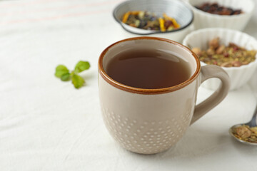Cup of hot freshly brewed tea on white fabric, closeup