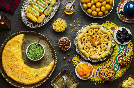 Arabic Cuisine: Middle Eastern desserts. Delicious collection of Ramadan traditional desserts. Served with tasty nuts, dried fruits, honey syrup and oriental tea. Top view with close up.